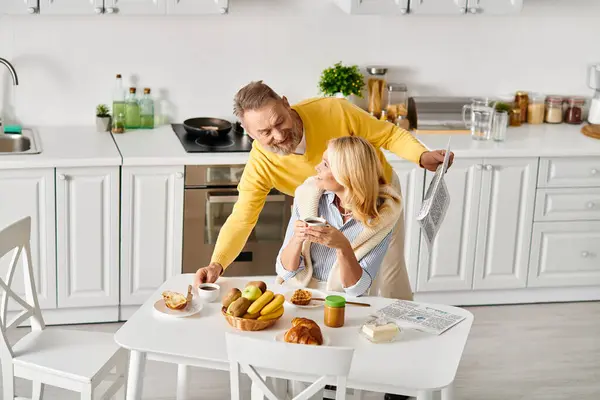Зрілий чоловік і його дружина позують разом у затишній кухні, розділяючи люблячий і щирий момент. — стокове фото