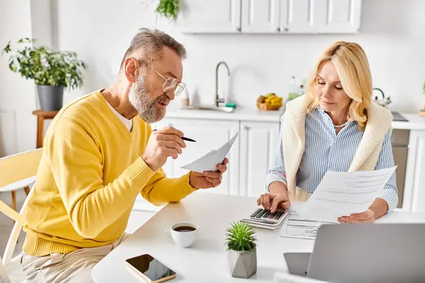 A couple in cozy homewear sit at a table, engrossed in paperwork, discussing and planning for the future. — Stock Photo
