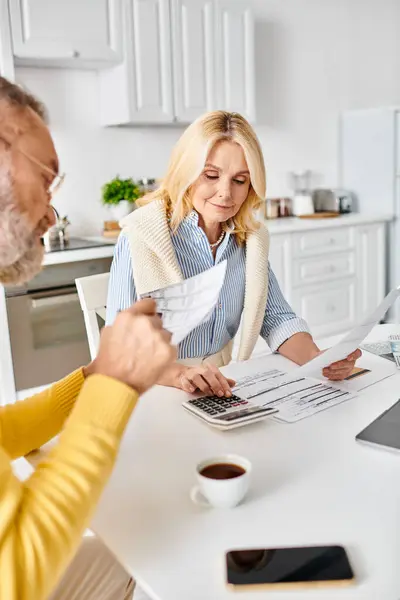 A mature loving couple in cozy homewear sitting together at a kitchen table, enjoying quality time in their home. — Stock Photo