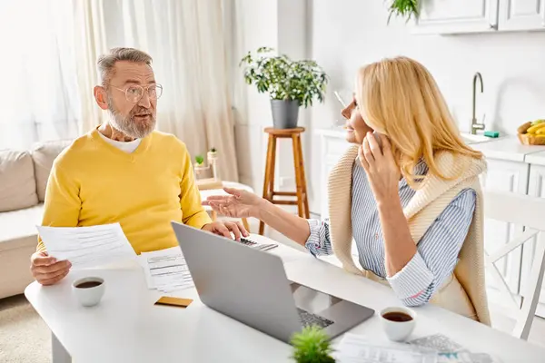 A man and woman in cozy homewear are sitting at a table, surrounded by papers, engaged in discussion and collaboration. — Stock Photo