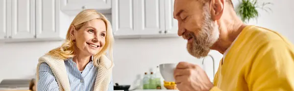 Зрелая любящая пара в уютной домашней одежде проводит время вместе на кухне, готовит и смеется. — стоковое фото