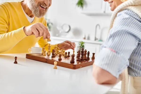 Un hombre y una mujer comprometidos en una batalla estratégica de ajedrez, reflexionando sobre sus próximos movimientos en un ambiente acogedor. - foto de stock