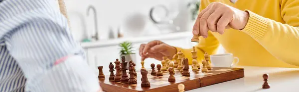 Um casal amável maduro em roupa de casa aconchegante profundamente focado em um jogo de xadrez, ponderando seus próximos movimentos. — Fotografia de Stock