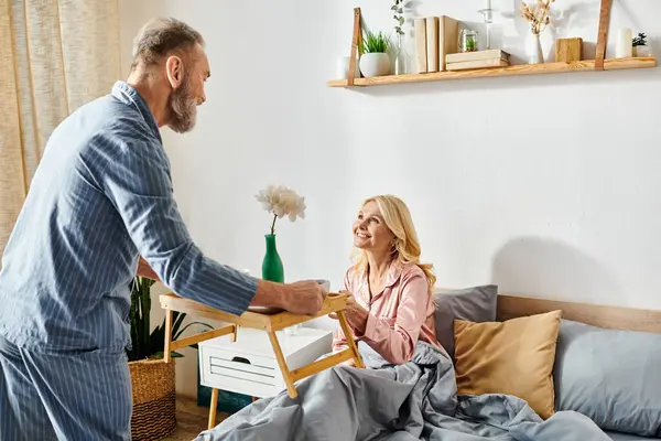 Man lovingly hands woman breakfast in cozy bedroom setting, creating a warm and intimate moment between the couple. — Stock Photo