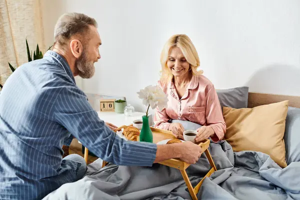 A mature man and woman in cozy homewear sitting together on a couch, enjoying each others company in a loving and relaxed atmosphere. — Stock Photo