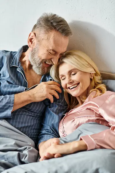 A mature loving couple in cozy homewear laying side by side in bed, sharing a peaceful moment together. — Stock Photo