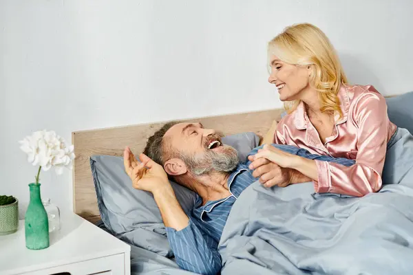 Un uomo e una donna, una coppia matura amorevole, in accogliente casalinghi pacificamente giacevano a letto insieme, condividendo un momento di intimità e vicinanza. — Foto stock