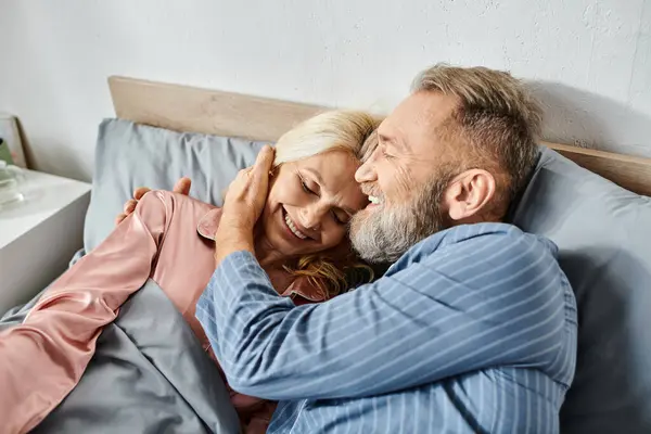 Ein reifes Liebespaar in kuscheliger Homewear, das zusammen im Bett liegt und einen ruhigen und intimen Moment miteinander teilt. — Stockfoto