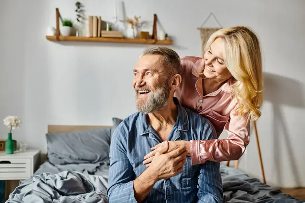 A man carrying a woman on his back in a cozy bedroom setting, showing love and unity in their relationship. — Stock Photo