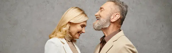 Un couple élégant et mature en tenue debonair pose ensemble sur un fond gris. — Photo de stock