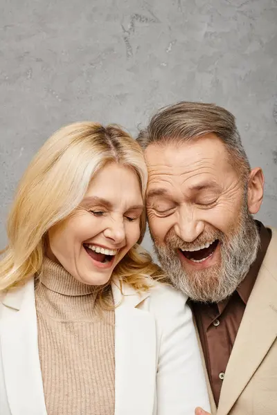 Зрілий чоловік і жінка, обидва елегантно одягнені, діляться мить радості, коли вони сміються разом. — стокове фото