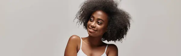 Красивая молодая афроамериканка с вьющимися волосами, ставящая позу в студии. — стоковое фото