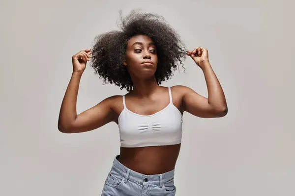 Uma bela jovem afro-americana com cabelo encaracolado está marcando uma pose em um estúdio. — Fotografia de Stock