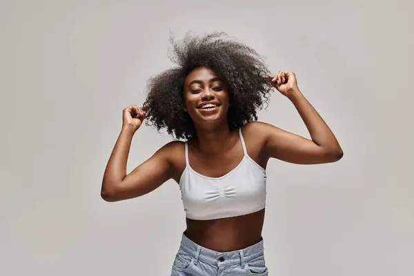 Une belle jeune femme afro-américaine aux cheveux bouclés coulant vers le haut, créant une scène fantaisiste et magique. — Photo de stock