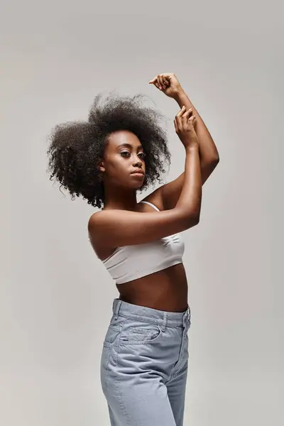 A young African American woman with a curly afro hairdo strikes a confident pose for a photo. — Stock Photo
