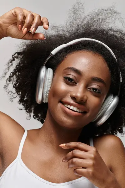 Young African American woman with curly hair listening to music through headphones, feeling the rhythm. — Stock Photo