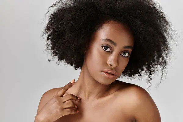 Une superbe Afro-Américaine aux cheveux bouclés dans un studio, posant pour un portrait. — Photo de stock