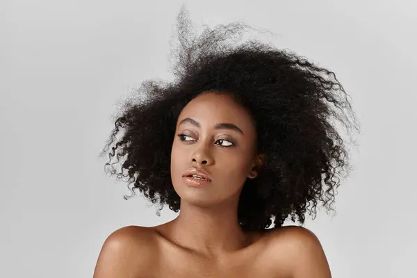 A beautiful young African American woman with curly hair poses confidently for a portrait in a studio setting. — Stock Photo