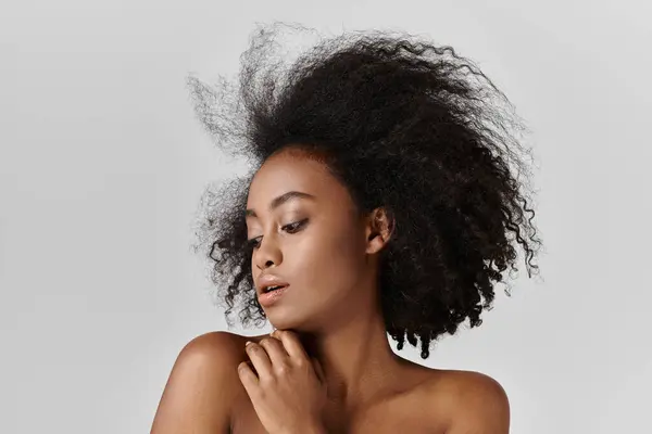 Eine atemberaubende junge Afroamerikanerin mit voluminösen Locken posiert für ein Porträt. — Stockfoto