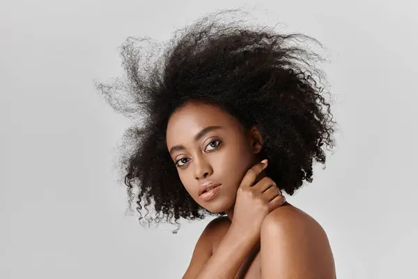 Una bella giovane donna afroamericana con i capelli ricci che colpisce una posa per un ritratto con i suoi capelli lucidi in mostra. — Foto stock