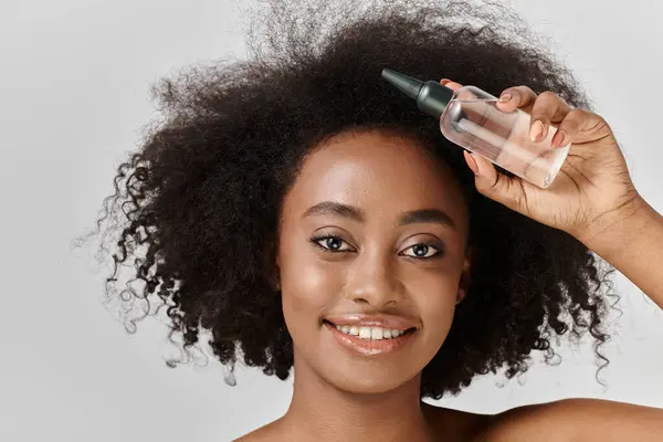 A beautiful young African American woman with curly hair in a studio setting, demonstrating a hair care concept. — Stock Photo