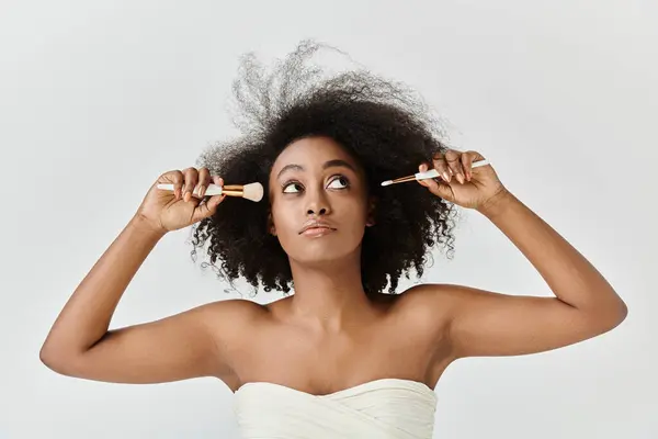 Une jeune afro-américaine aux cheveux bouclés utilise une brosse avec un accent sur les soins de la peau. — Photo de stock
