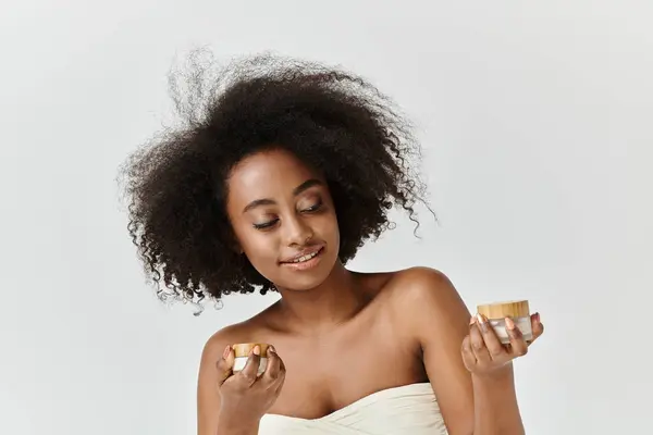 Uma jovem afro-americana cativante com cabelo encaracolado segurando um pote de creme — Fotografia de Stock