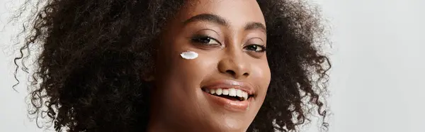 Una hermosa joven afroamericana con el pelo rizado, que transmite felicidad pura con una sonrisa brillante en su cara. - foto de stock