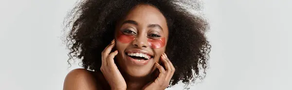 A beautiful young African American woman with curly hair showcases a skin care concept — Stock Photo