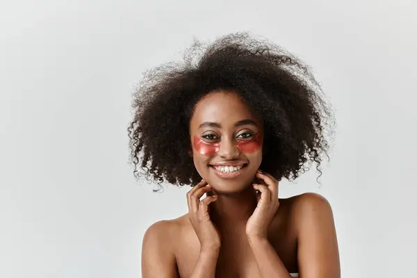 Une belle jeune femme afro-américaine aux cheveux bouclés présente des patchs oculaires — Photo de stock