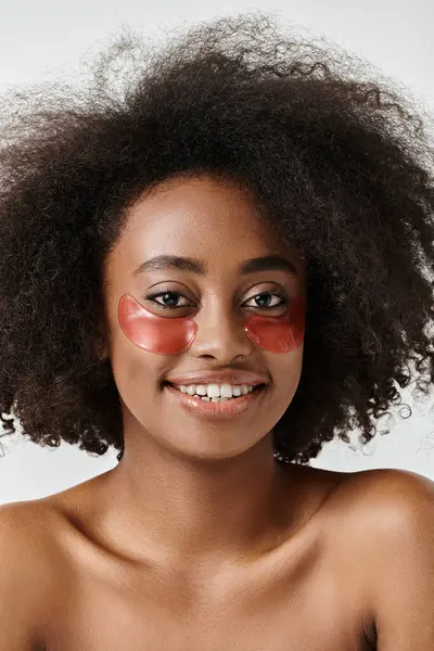 A stunning African American woman with curly hair wearing a bold red eye patch looks fierce and confident. — Stock Photo