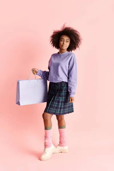 A fashionable African American girl with curly hair holding shopping bags in a studio setting. — Stock Photo