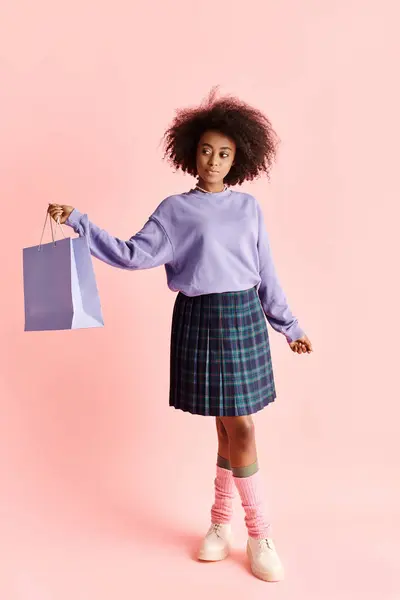 A stylish African American woman in a skirt holds a shopping bag, exuding fashion and elegance in a studio setting. — Stock Photo