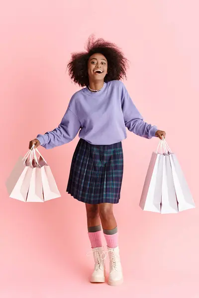 African American woman with curly hair, wearing a skirt, holding shopping bags in a stylish pose. — Stock Photo