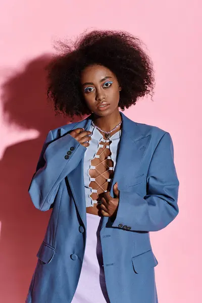 A stylish young African American woman with curly hair wearing a blue jacket and white dress in a studio setting. — Stock Photo