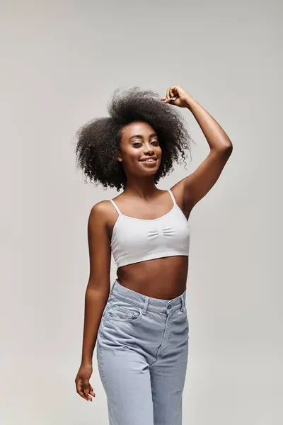 Uma jovem mulher afro-americana deslumbrante com cabelo encaracolado, estilizada em um afro, posa com confiança para uma câmera. — Fotografia de Stock