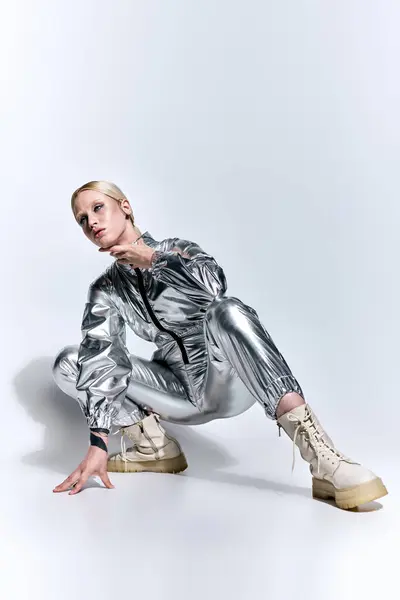 Bela mulher em prata traje futurista posando em movimento no fundo cinza e olhando para longe — Fotografia de Stock