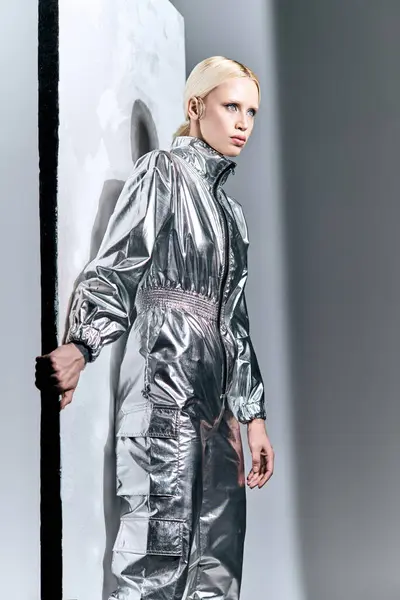 Gut aussehende blonde Frau in außergewöhnlicher futuristischer Kleidung posiert an der Wand und schaut weg — Stockfoto