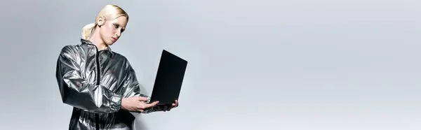 Extraordinary woman with makeup in futuristic clothes looking at her laptop on gray backdrop, banner — Stock Photo