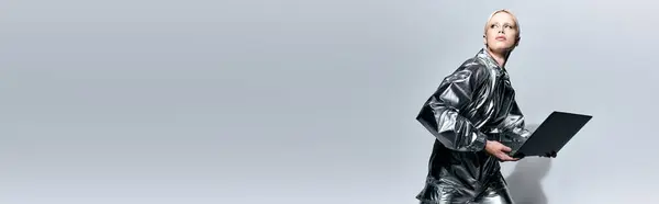 Attraente donna particolare in abbigliamento robotico in posa in movimento con il computer portatile e guardando altrove, banner — Foto stock