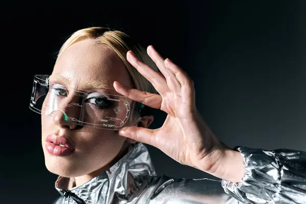 Attraktive sonderbare Frau in Science-Fiction-Brille und silberner Kleidung, die vor dunklem Hintergrund in die Kamera blickt — Stockfoto