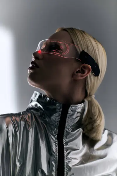 Belle femme avec des lunettes futuristes en costume d'argent robotique regardant loin sur fond gris — Photo de stock