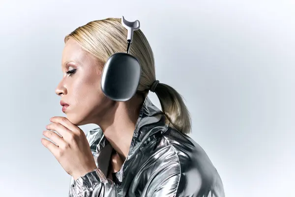 Extraordinary good looking woman with headphones in futuristic silver attire enjoying music — Stock Photo