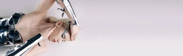 Bella donna bizzarra con i capelli biondi in argento abbigliamento futuristico sdraiato sul pavimento, banner — Foto stock