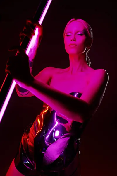 Modelo feminino peculiar boa aparência em traje futurista metálico segurando vibrante rosa LED lâmpada stick — Fotografia de Stock