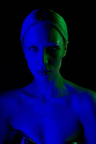 Schöne futuristische Frau in metallischer Science-Fiction-Kleidung posiert im Blaulicht und blickt in die Kamera — Stockfoto