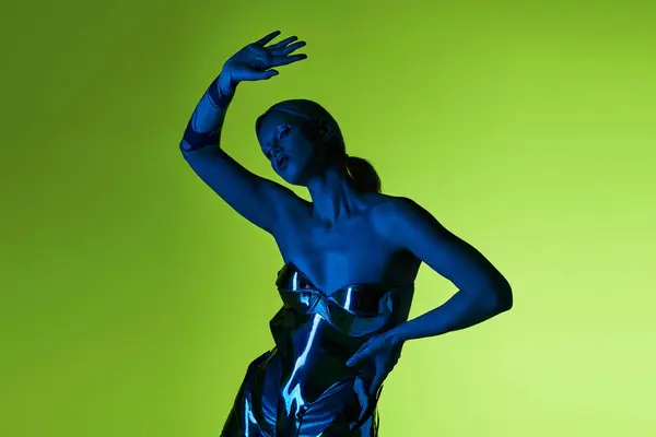Peculiar alluring woman in futuristic sci fi attire posing in blue lights on green backdrop — Stock Photo
