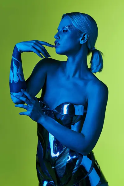 Peculiar attractive woman in futuristic sci fi attire posing in blue lights on green backdrop — Stock Photo