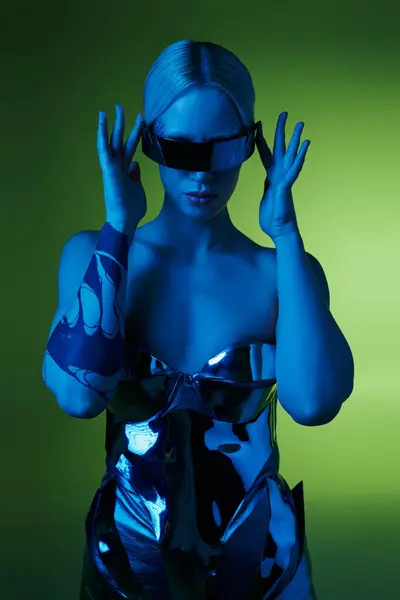 Futuristische Frau in silberner Roboterkleidung mit Science-Fiction-Sonnenbrille posiert in Lichtern vor grünem Hintergrund — Stockfoto