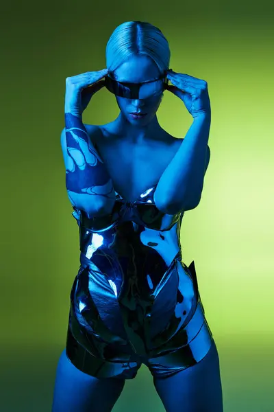 Femme futuriste en costume robotique argenté avec lunettes de soleil science-fiction posant dans des lumières sur fond vert — Photo de stock